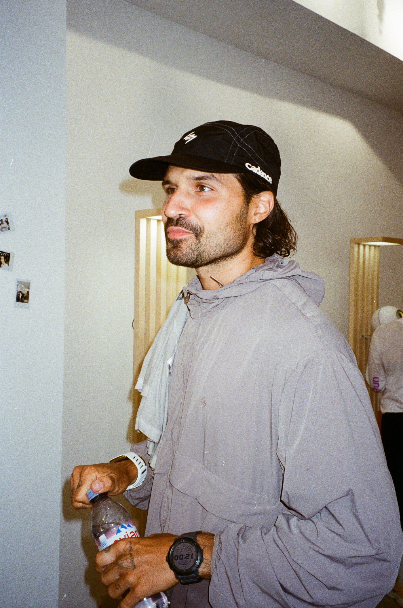 A man in a cap holds a water bottle at an event.