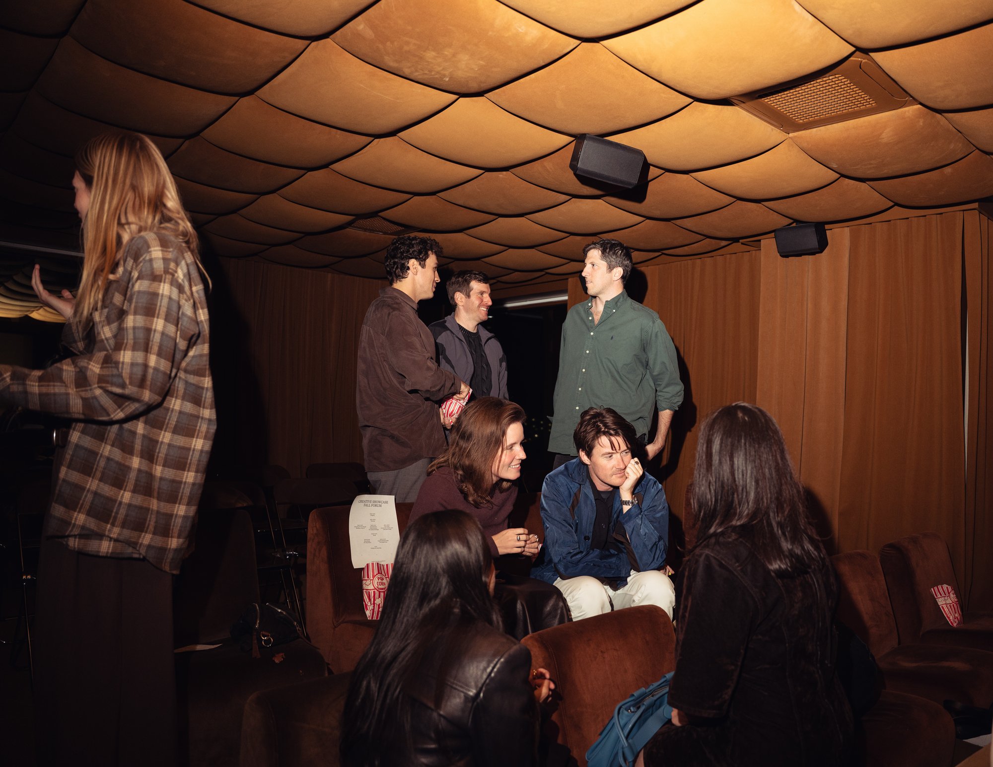 A cinema room full with audience and speakers sitting on the stage