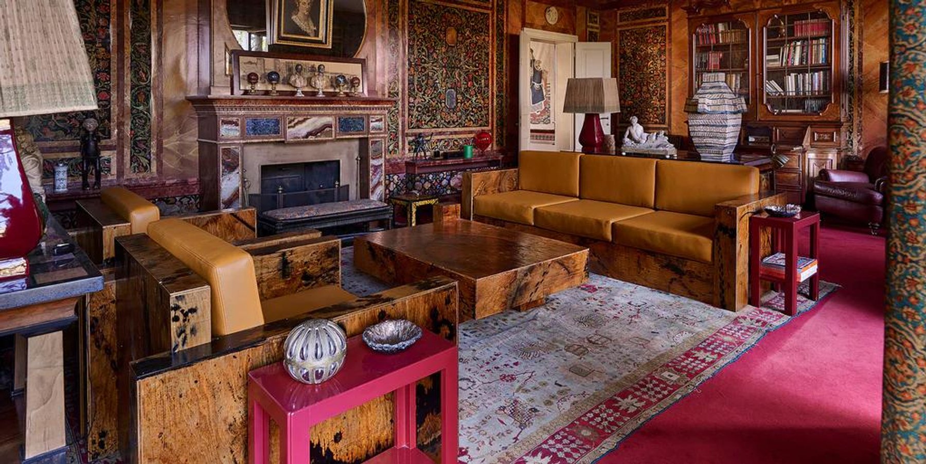 A wood panelled room with a fireplace, tapestries on the walls and a pink table.
