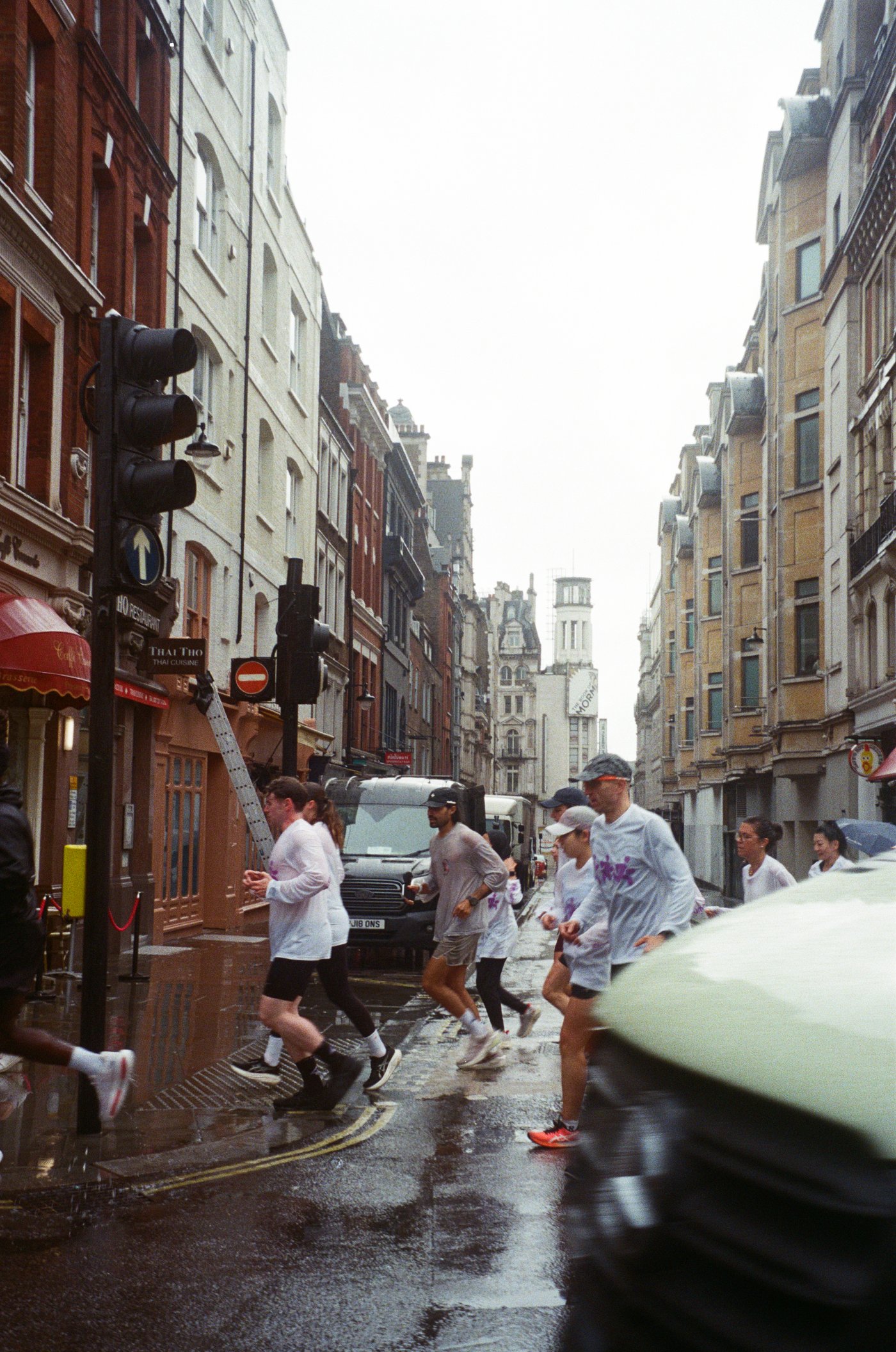 Runners crossing a London street in the rain.