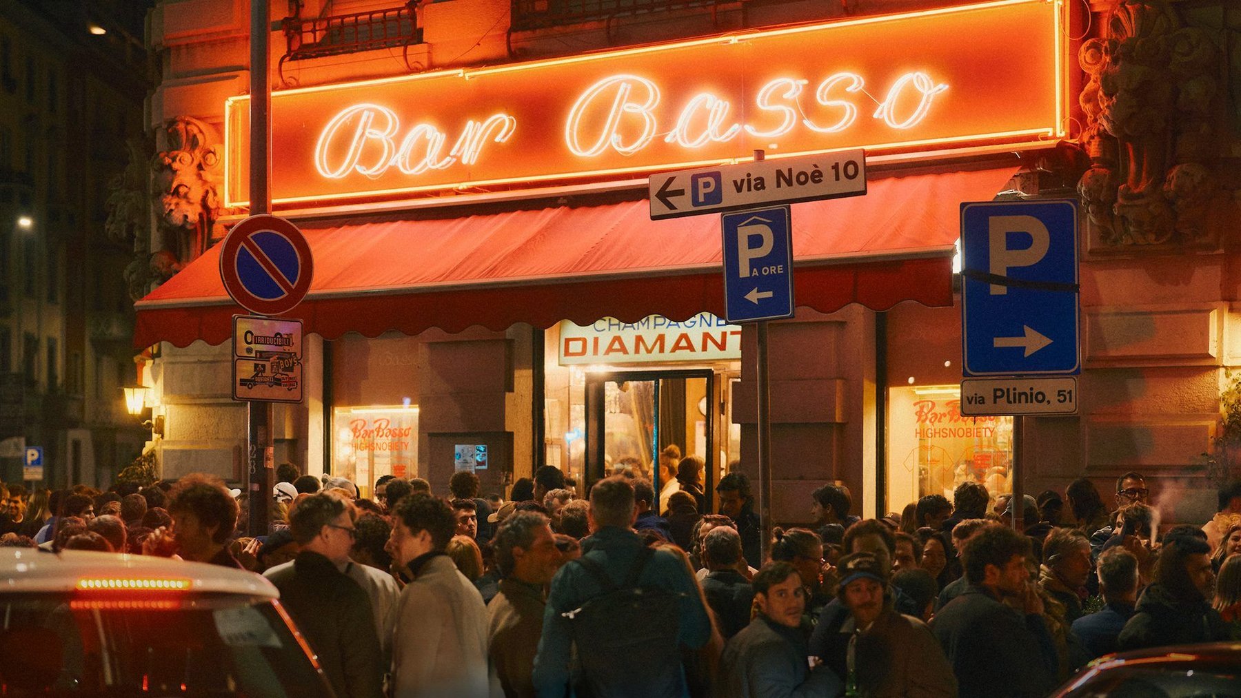 The Bar Basso neon sign at night, with a crowd on the pavement below it.