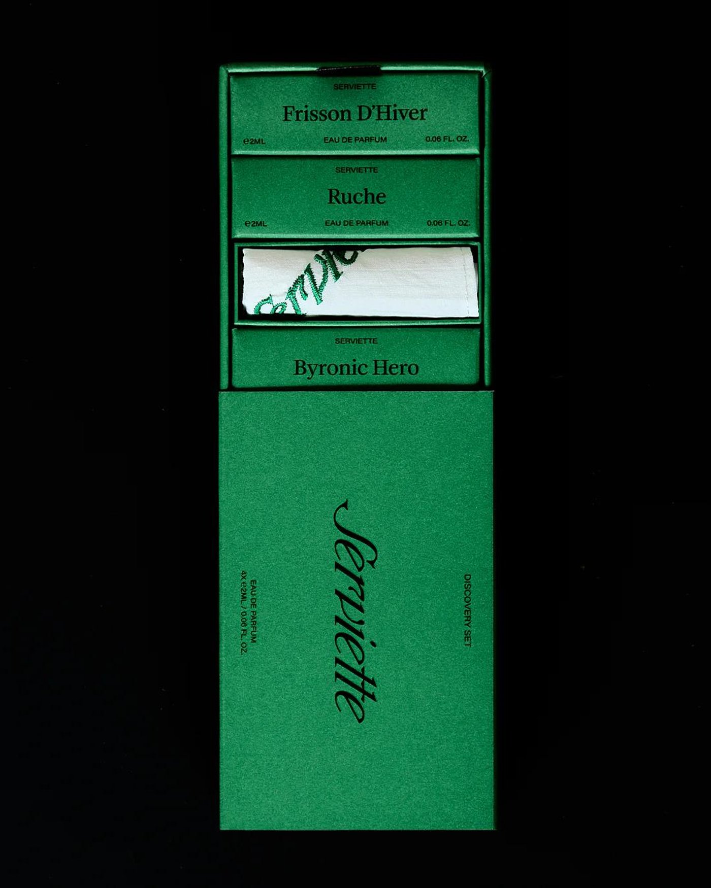 A green box of perfume samples, opened to show the vials and a folded napkin.