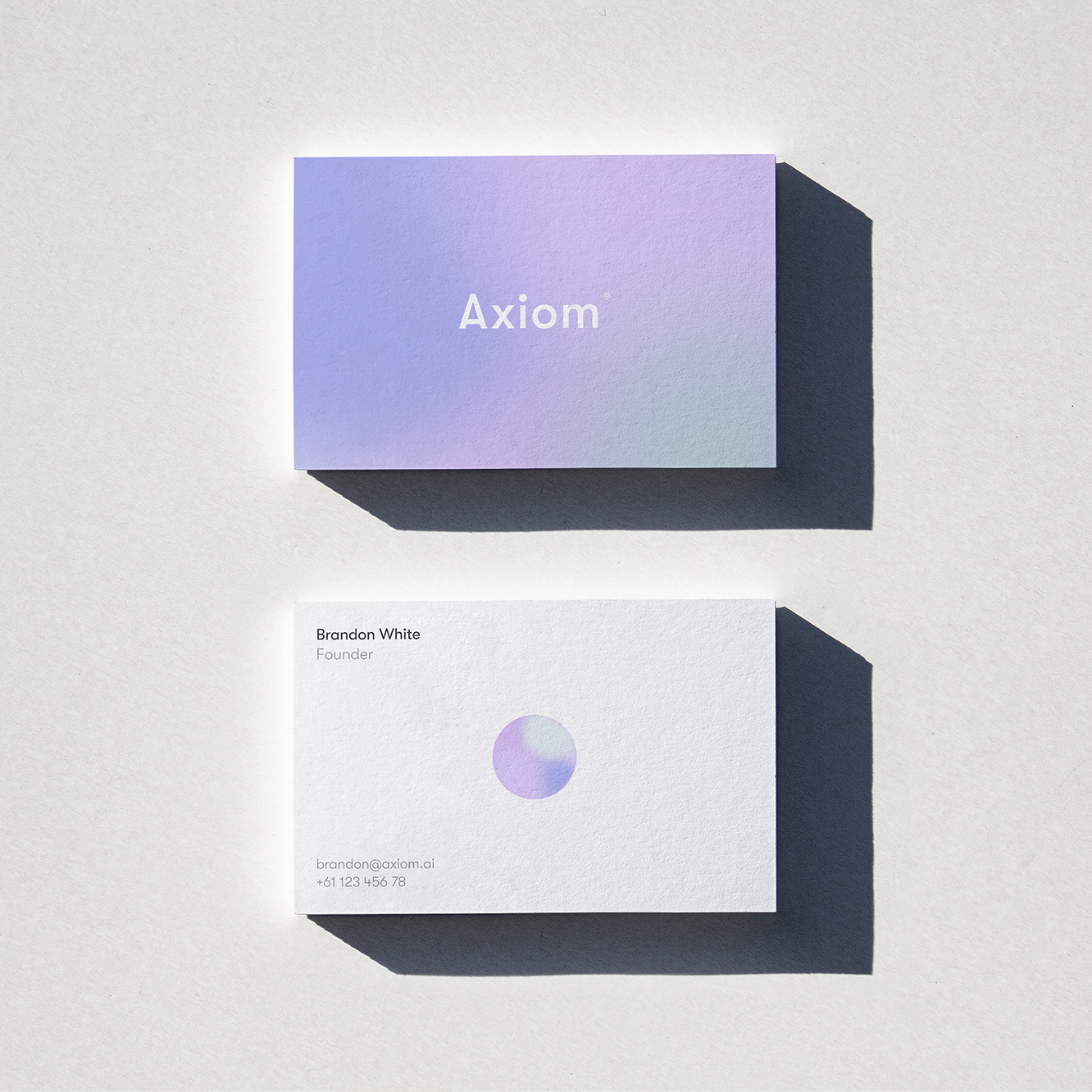 Axiom business cards with the lilac gradient and the orb