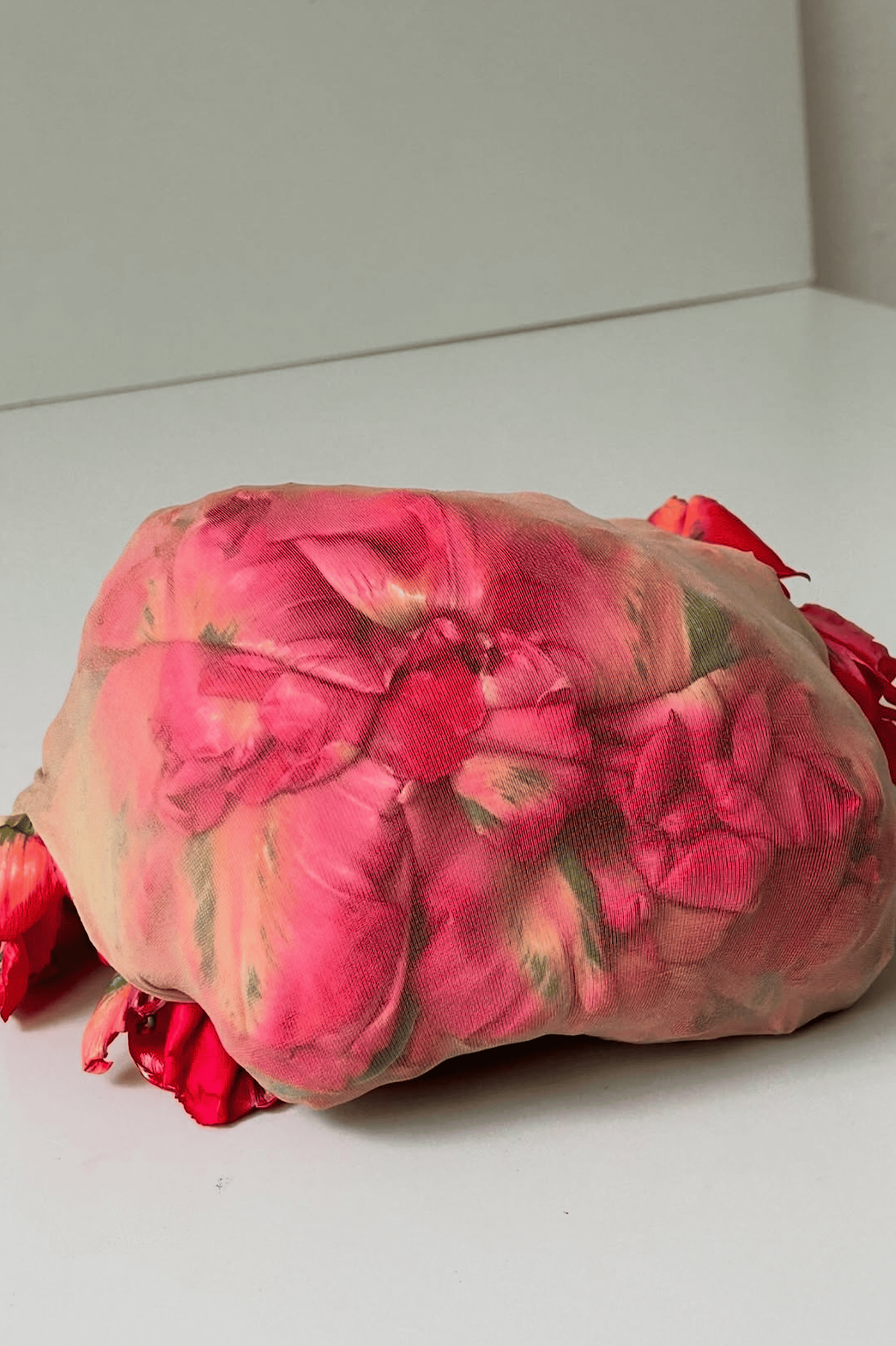 A soft sculpture wrapped in pink floral fabric, standing on a white table.