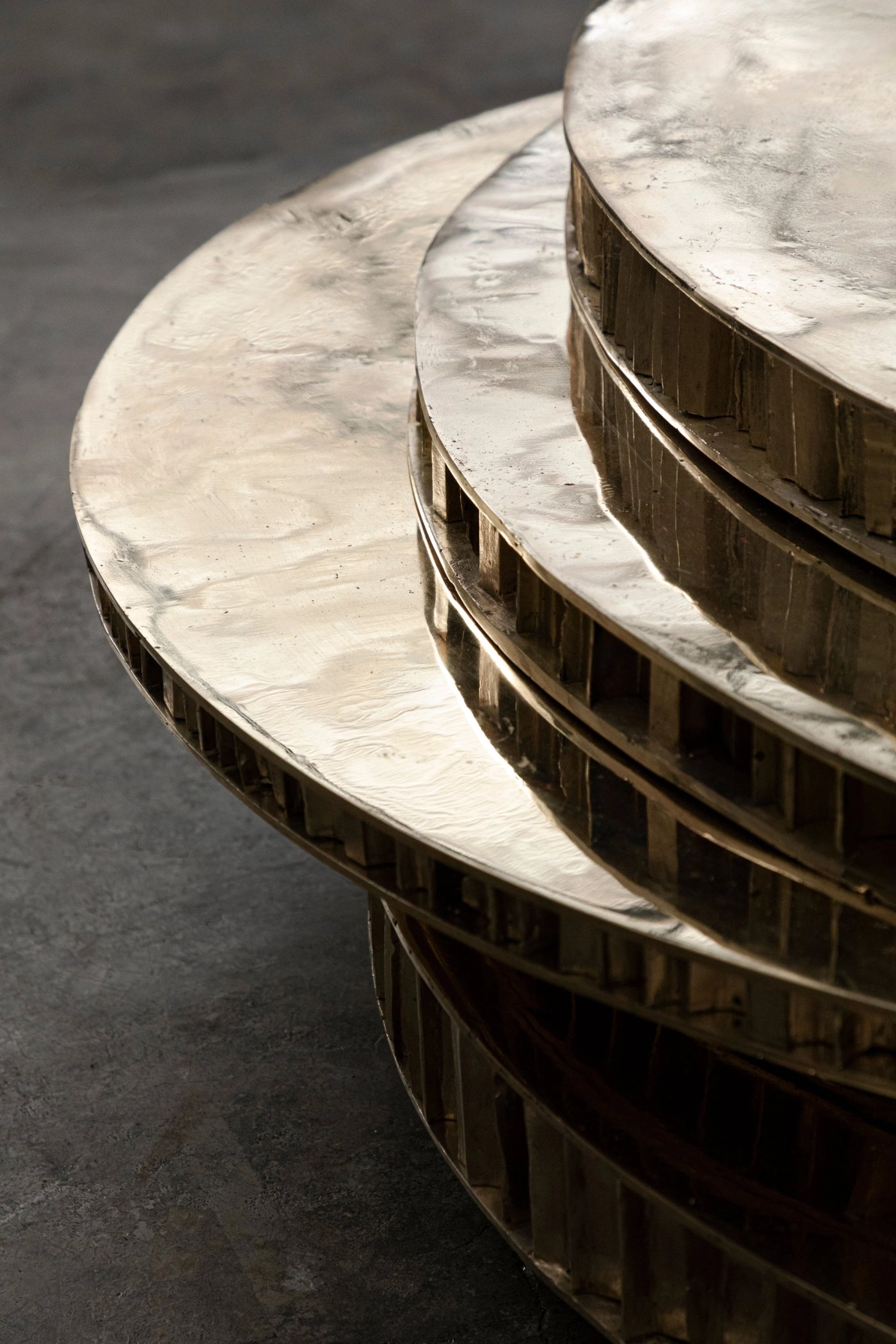 A stack of polished brass discs of different sizes, forming a low table.