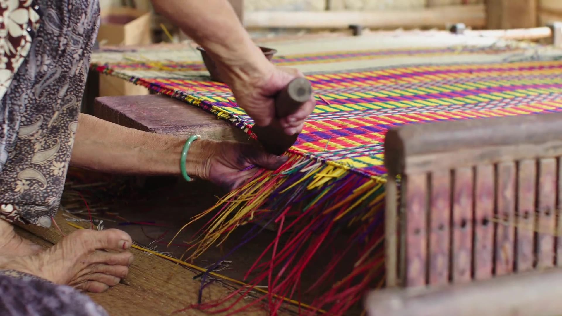 Hands weaving a sedge mat on a loom in Long An