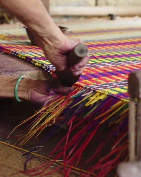 Hands weaving a sedge mat on a loom in Long An