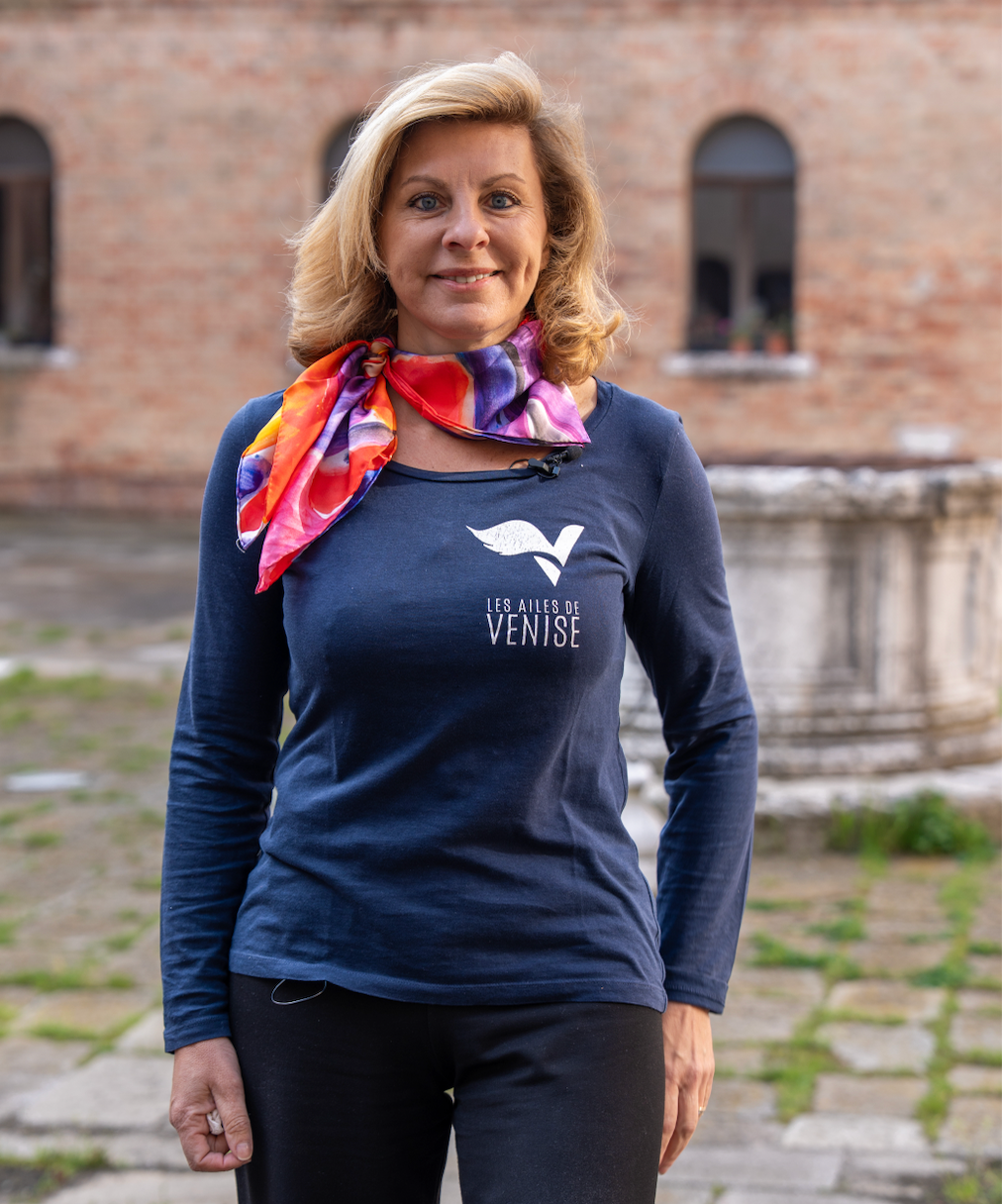 Isabelle Kahna, CEO des Ailes de Venise, portant le t-shirt de sa marque dans une cour vénitienne