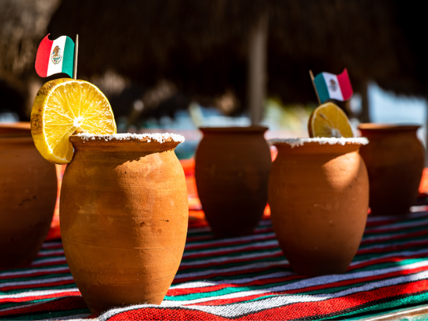 Clay drinking cups with salted rim, lemon wedge and Mexico flag