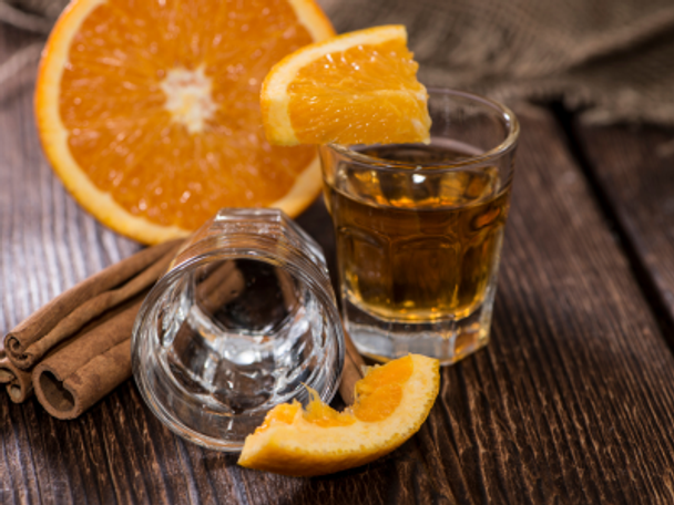 Glass of Anjeo sitting on table with orange slices and cinnamon sticks