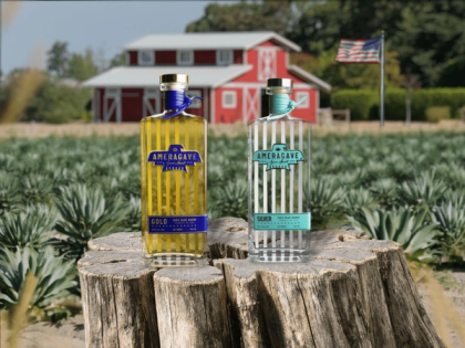 bottles of Ameragave sitting on a tree stump in front of an agave field with a red barn and an American flag