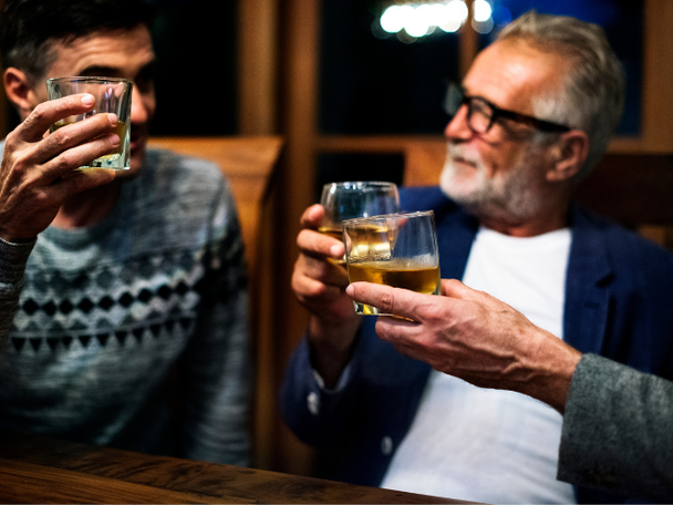 Three people holding up cups of tequila while having a conversation