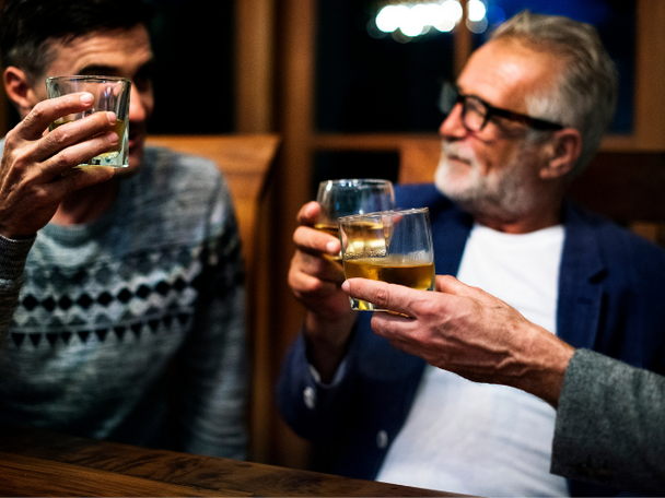 Three people holding up cups of tequila while having a conversation