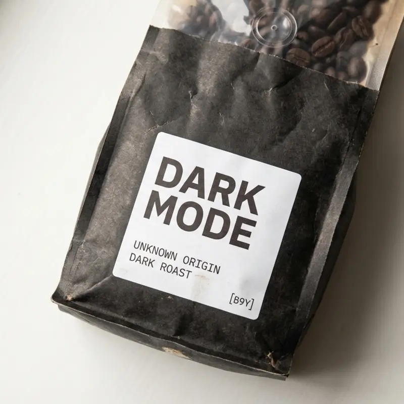 Specialty coffee bag labeled 'Dark Mode' with a dark roast level, photographed on a bone/off-white background.