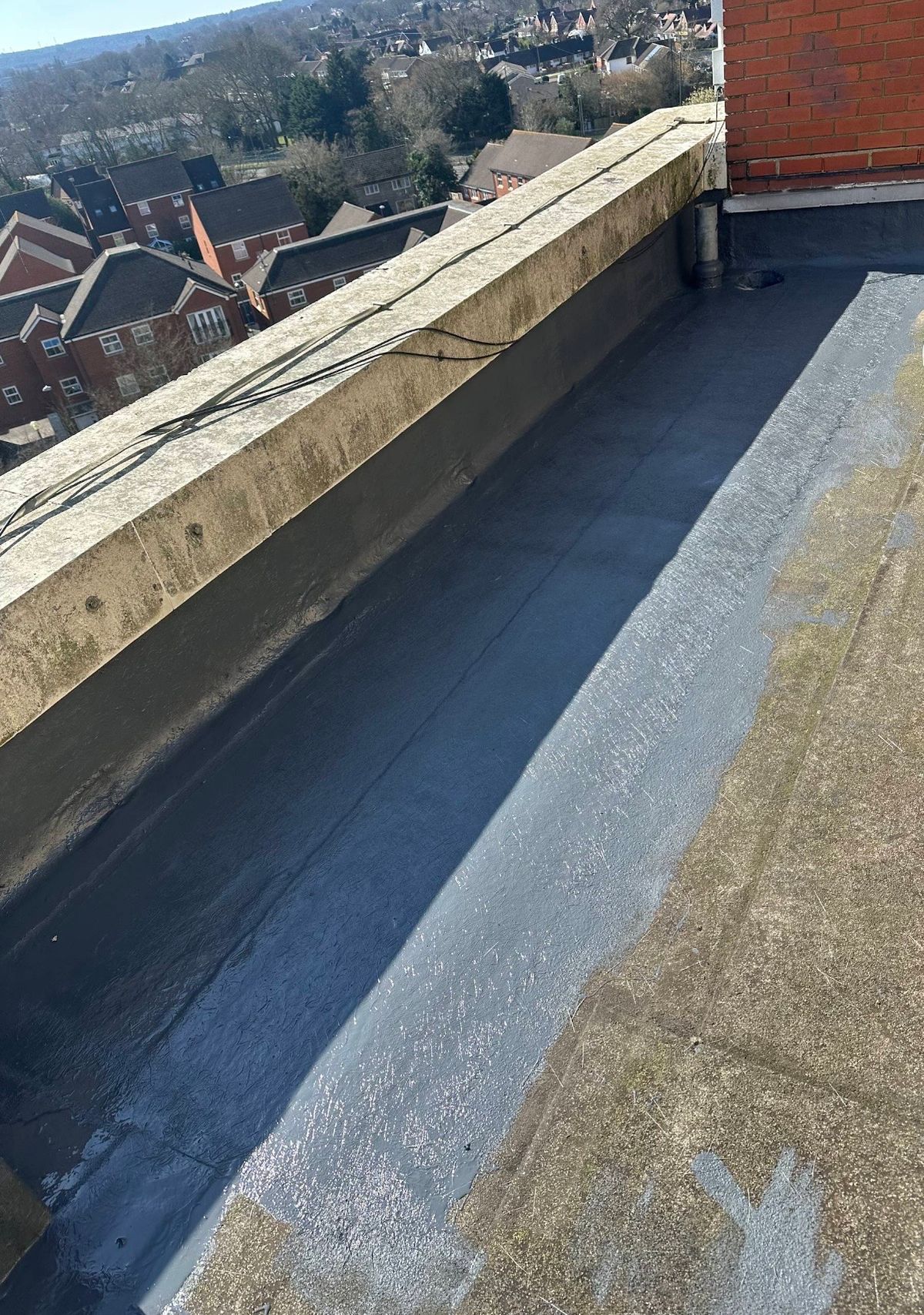 Liquid waterproofing applied along the roof perimeter and upstand to protect a vulnerable edge detail.