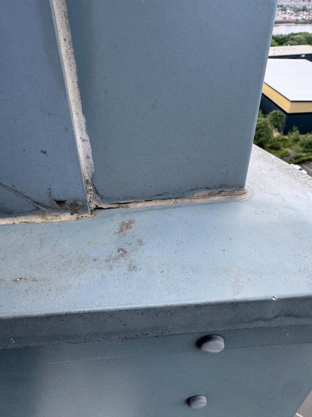 Visible gaps and deteriorated sealant at the junction between vertical aluminium cladding and horizontal flashing on a high-rise residential building in Newcastle, prior to repair.
