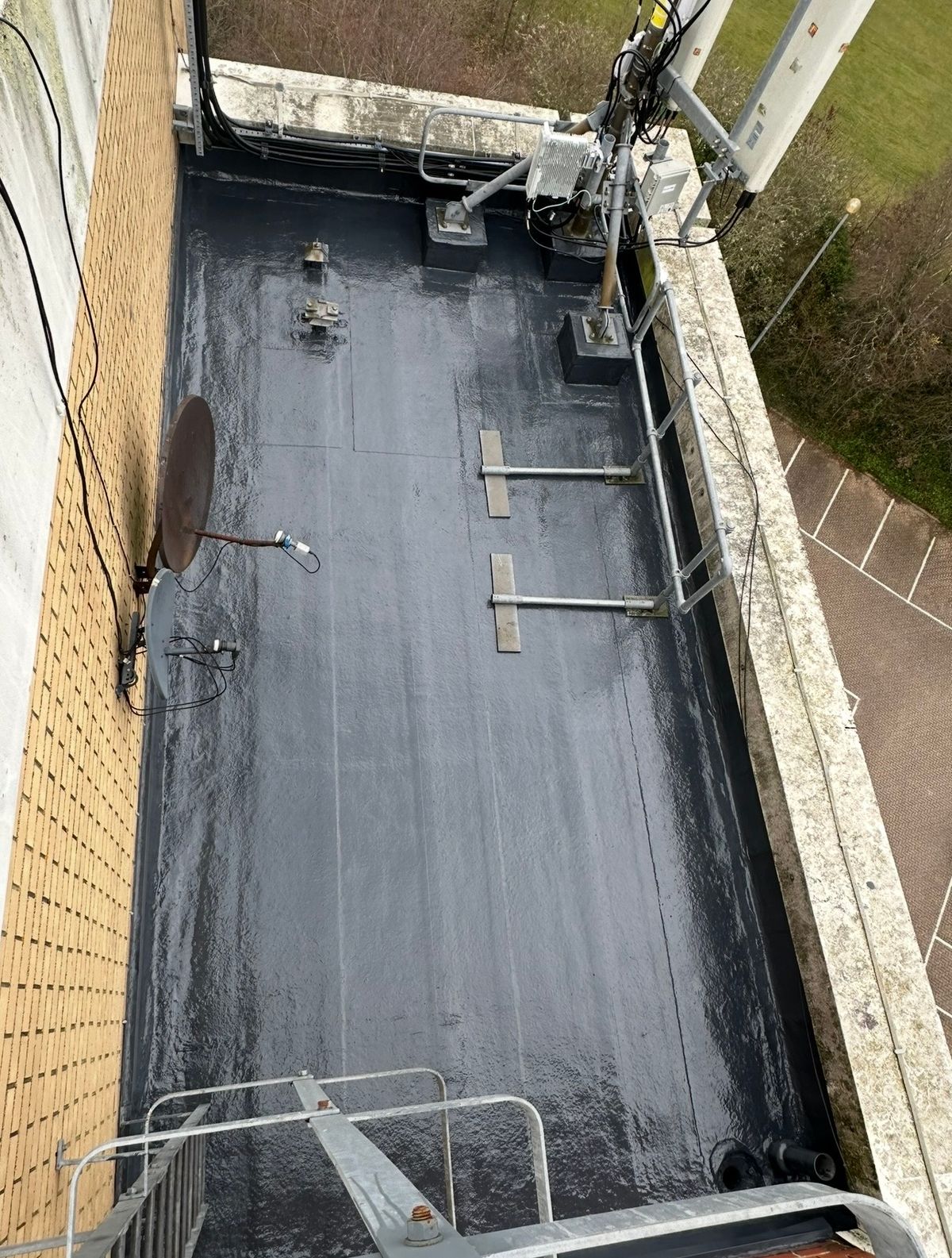 Completed waterproofing across the secondary flat roof, including perimeter upstands, drainage points and rooftop equipment bases.