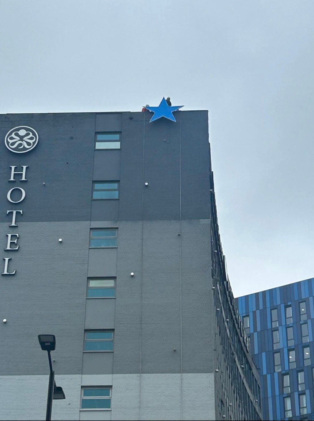 Rope access technicians reinstalling the restored Newcastle Breweries Blue Star on the Sandman Signature Newcastle Hotel.
