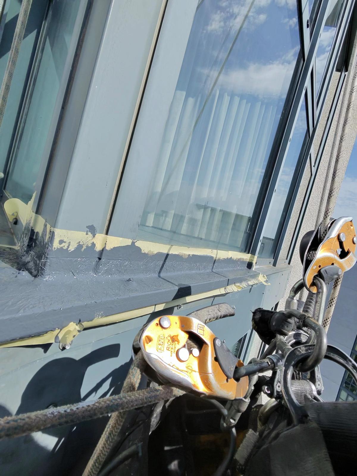 Ultraflex liquid waterproofing applied to external window sill and aluminium frame junctions on a high-rise residential building in Newcastle, using specialist rope access techniques.