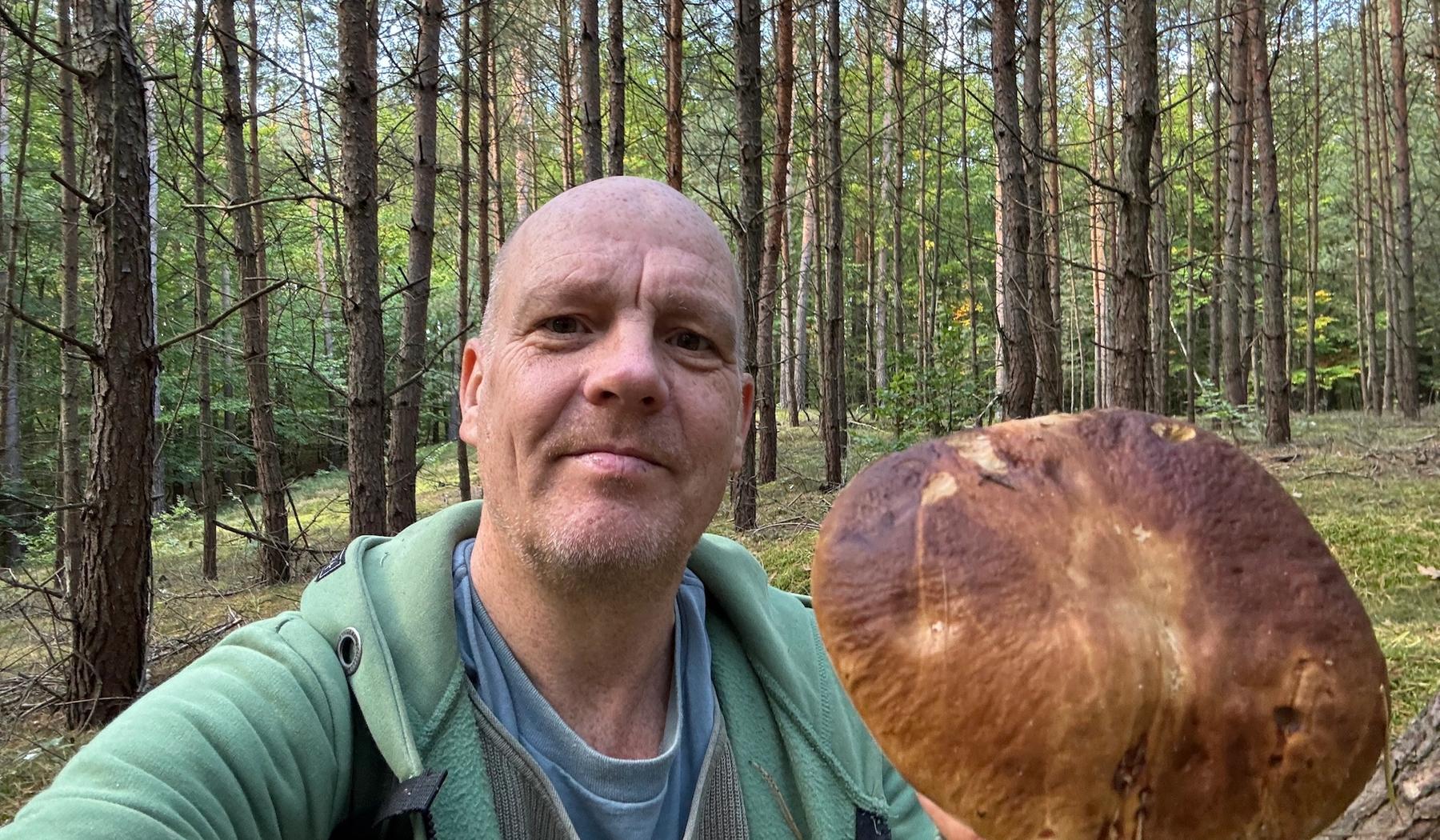 George Brasch im Wald mit einem großen Steinpilz in der Hand während einer Pilzwanderung.