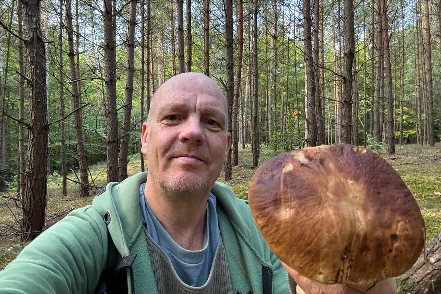 George Brasch im Wald mit einem großen Steinpilz in der Hand während einer Pilzwanderung.