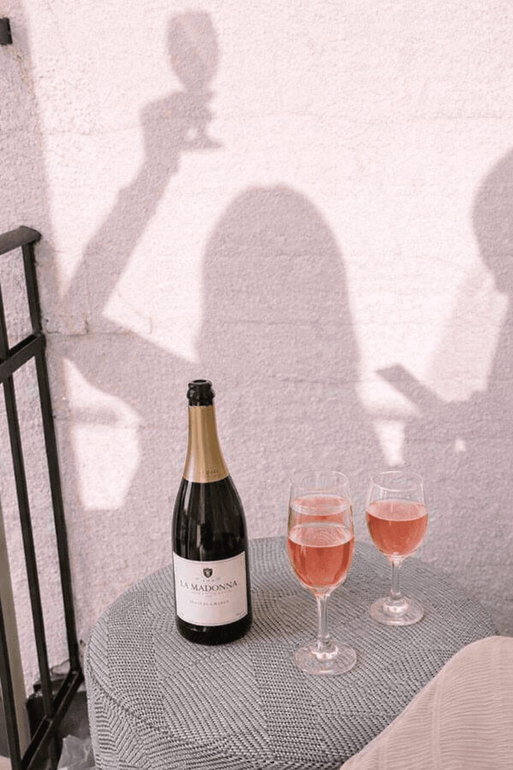 Bottle of sparkling wine and two glasses of pink bubbly on a terrace table