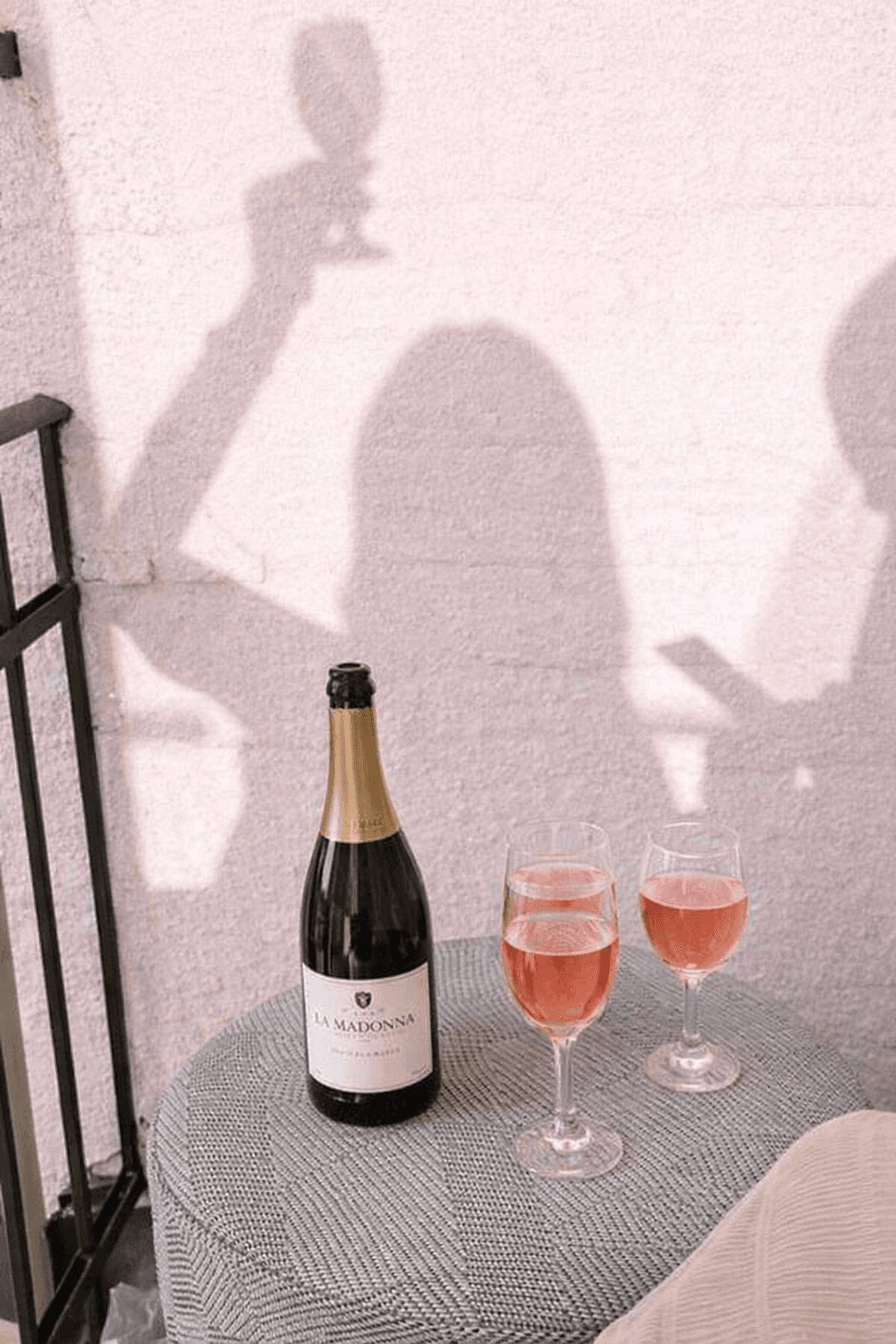 Bottle of sparkling wine and two glasses of pink bubbly on a terrace table