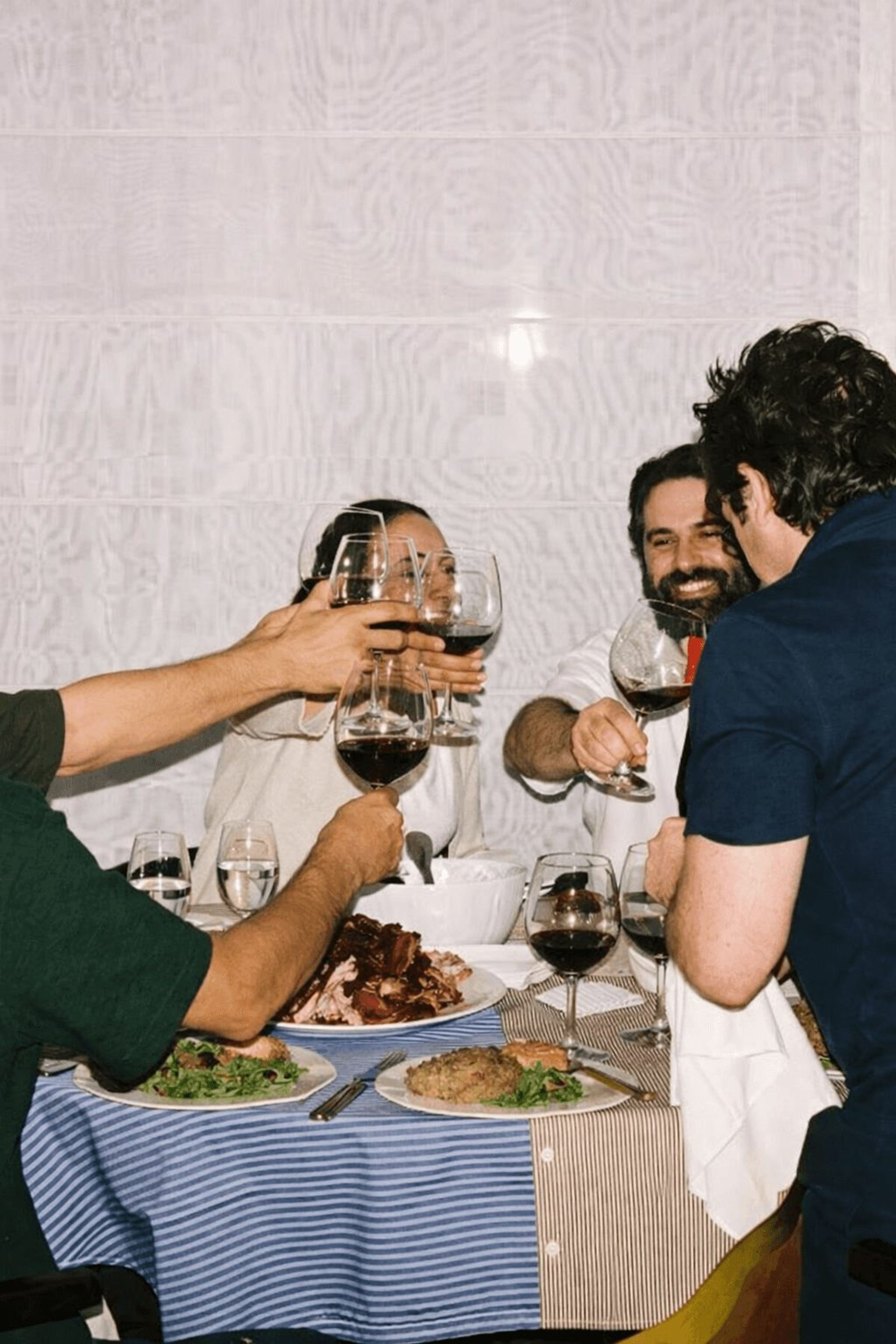 Friends toasting with red wine over a shared dinner