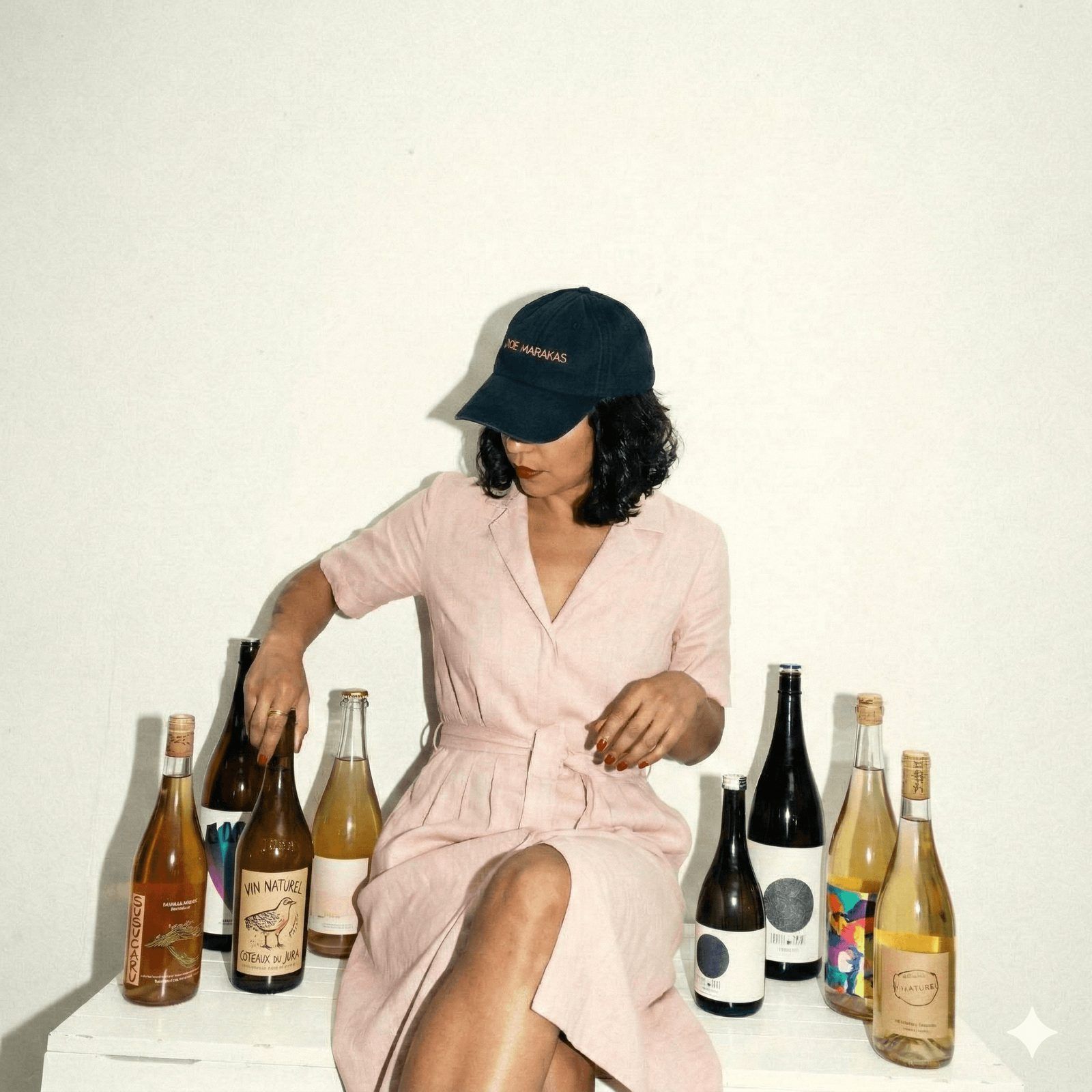 Woman in a cap sitting among bottles of natural wine