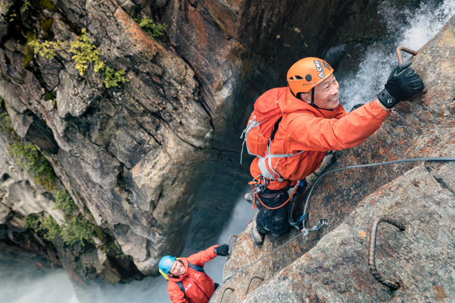 A guest climbing beside a waterfall