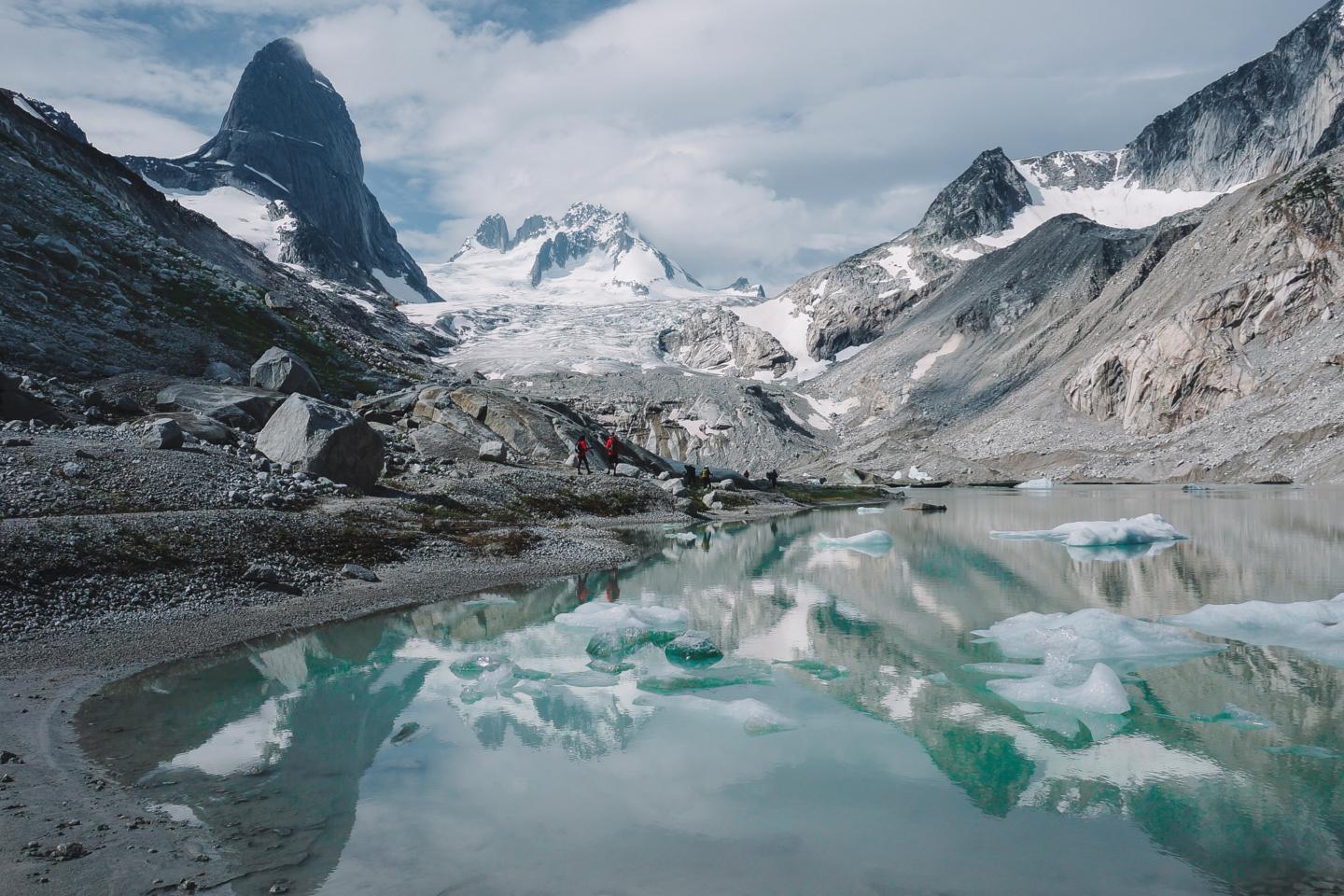 standing at the edge of a glacial lake withe the glacier in the background