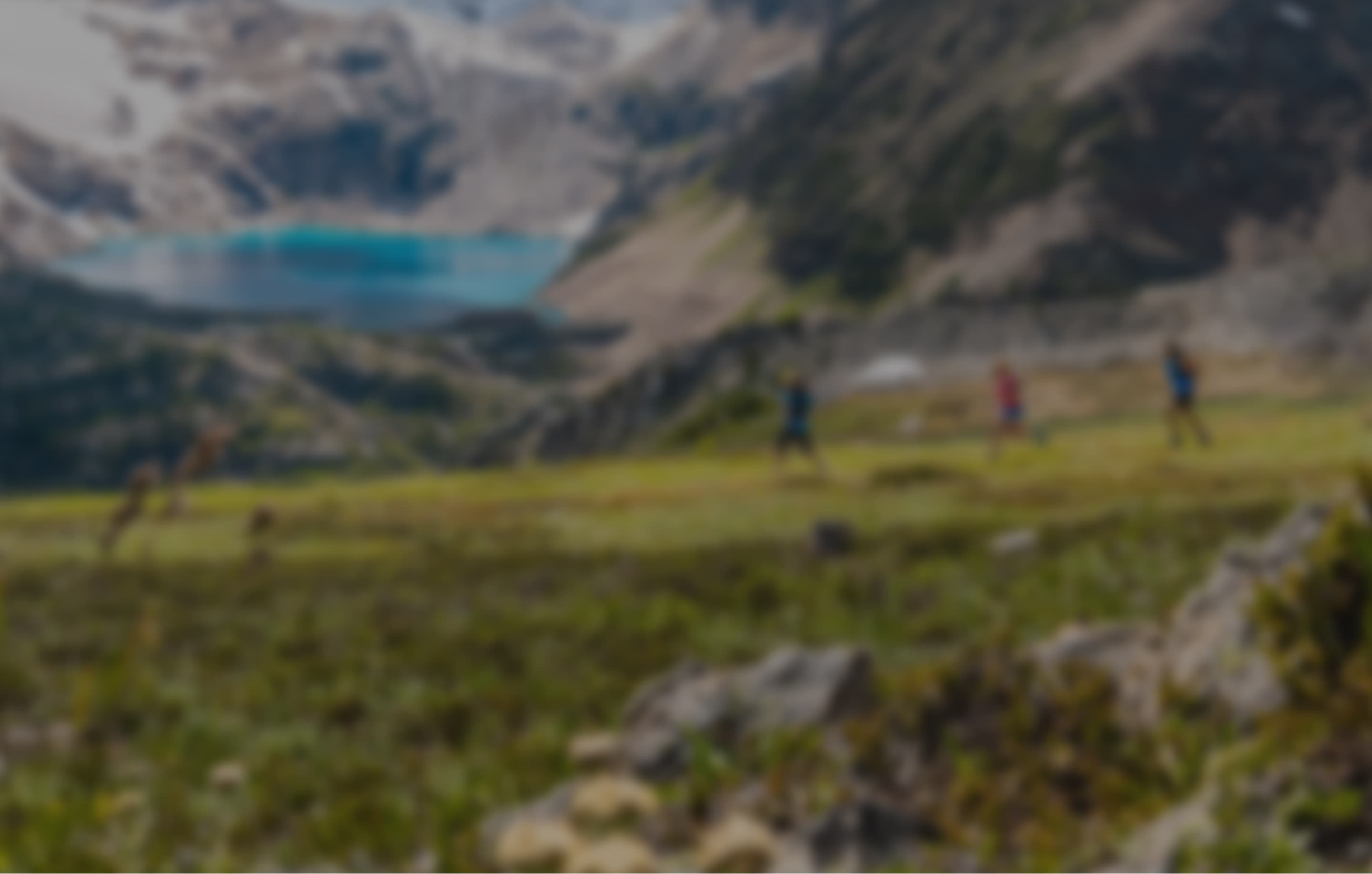 A group of people with a helicopter above and mountains in the background