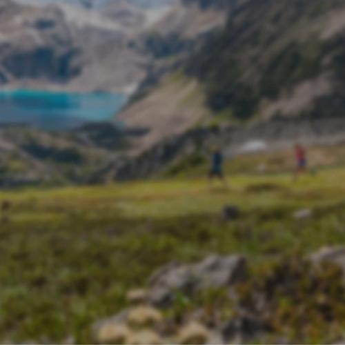 A group of people with a helicopter above and mountains in the background