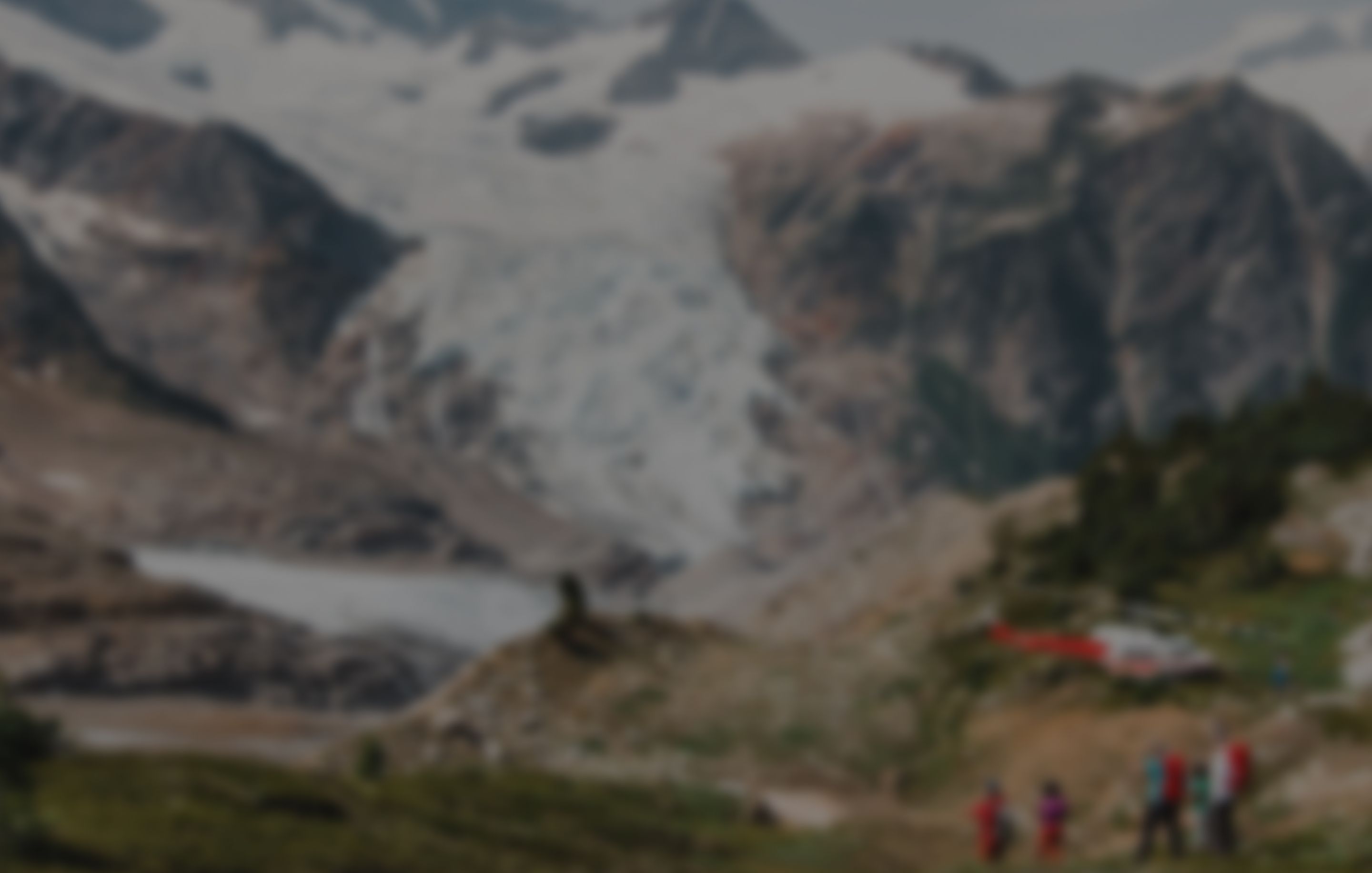A group of people with a helicopter above and mountains in the background