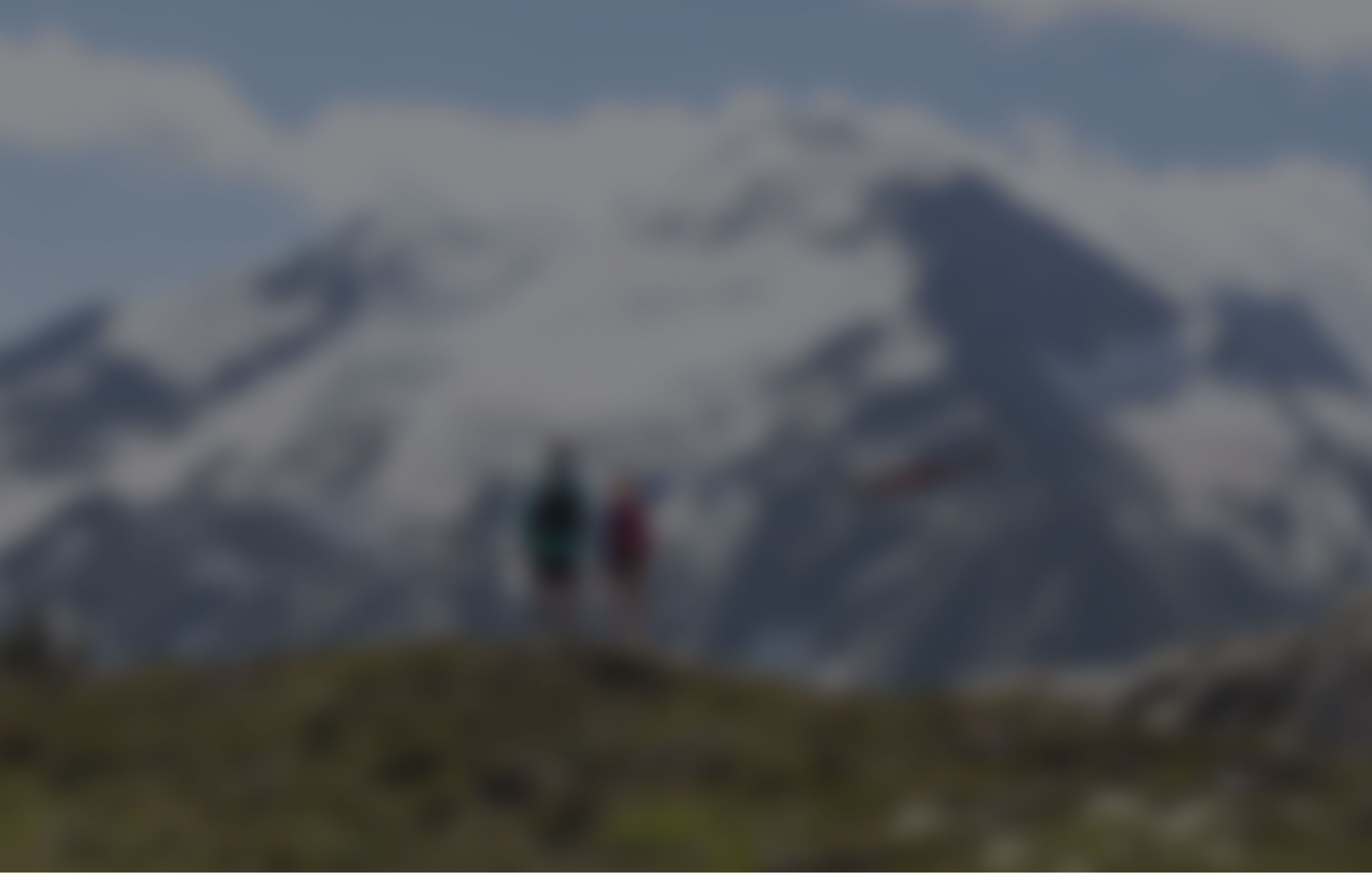 Two people watching a helicopter go by in a valley of mountains