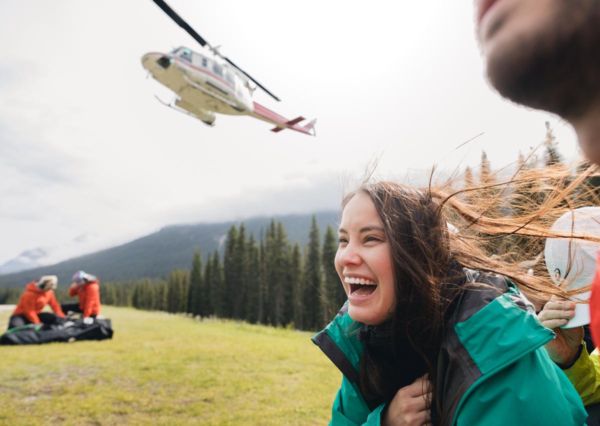 woman smiling as a helicopter takes off above her