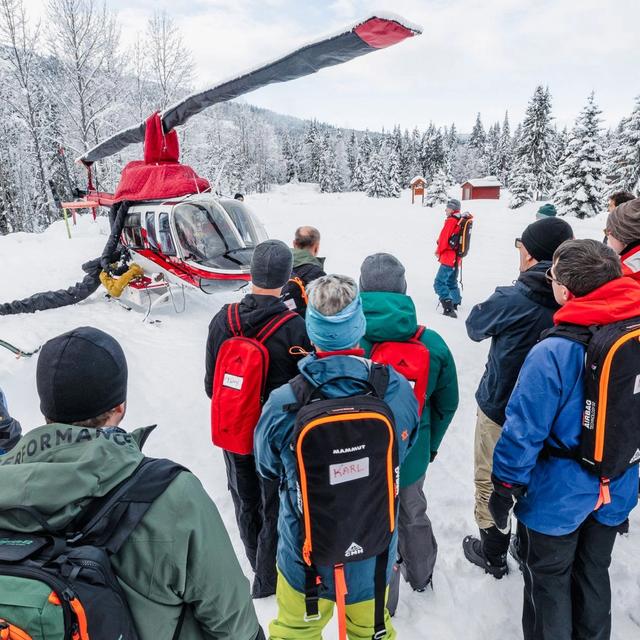 A group of people stand outside of a helicopter for a safety briefing