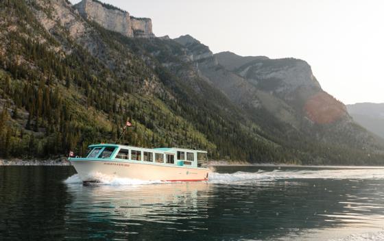 small enclosed boat on a lake with mountains in the background