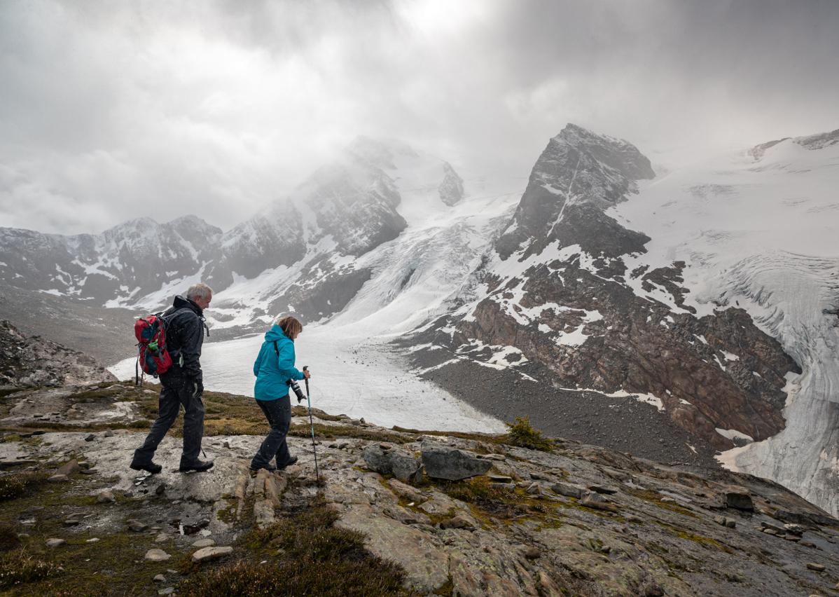 two people walking with a glacier in the background