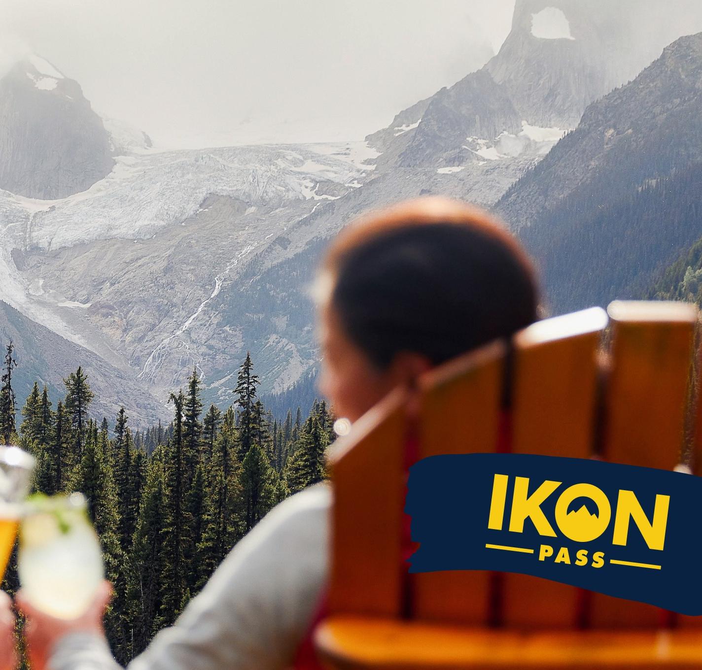 two people sit on lawn chairs looking out at a mountain view, and cheers a beverage