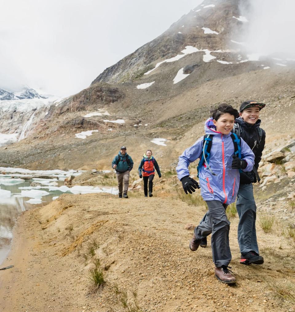 two kids running on a trail with two adult trailing behind them