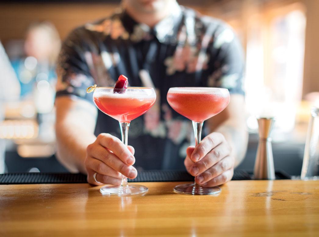 A bartender serving two beverages