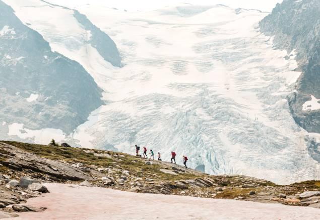 A group of people hiking on a ridge with a glacier in the background