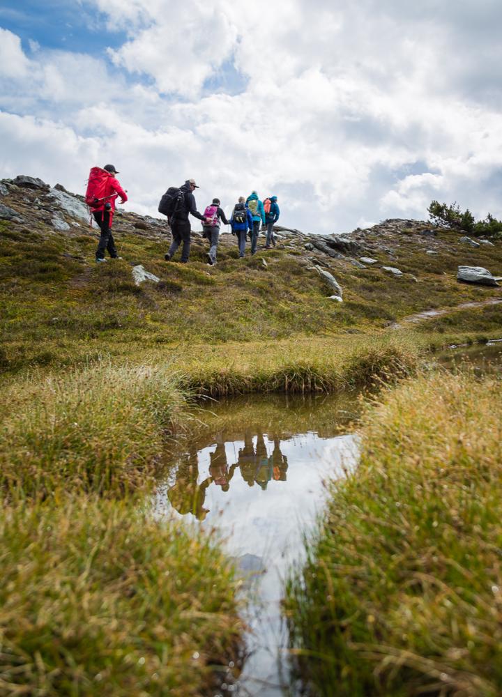 a group of people walking in the background and their reflection in a stream in the foreground