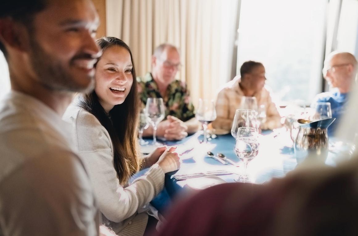 A group of people sitting around a table smiling