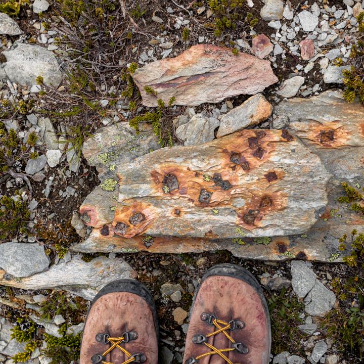 looking down at a set of hiking boots on rocks