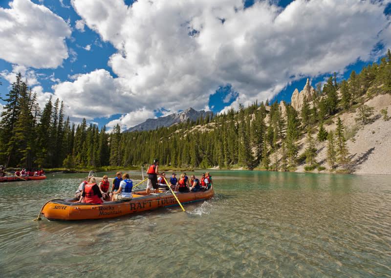 a group of people in am orange raft on a shallow river