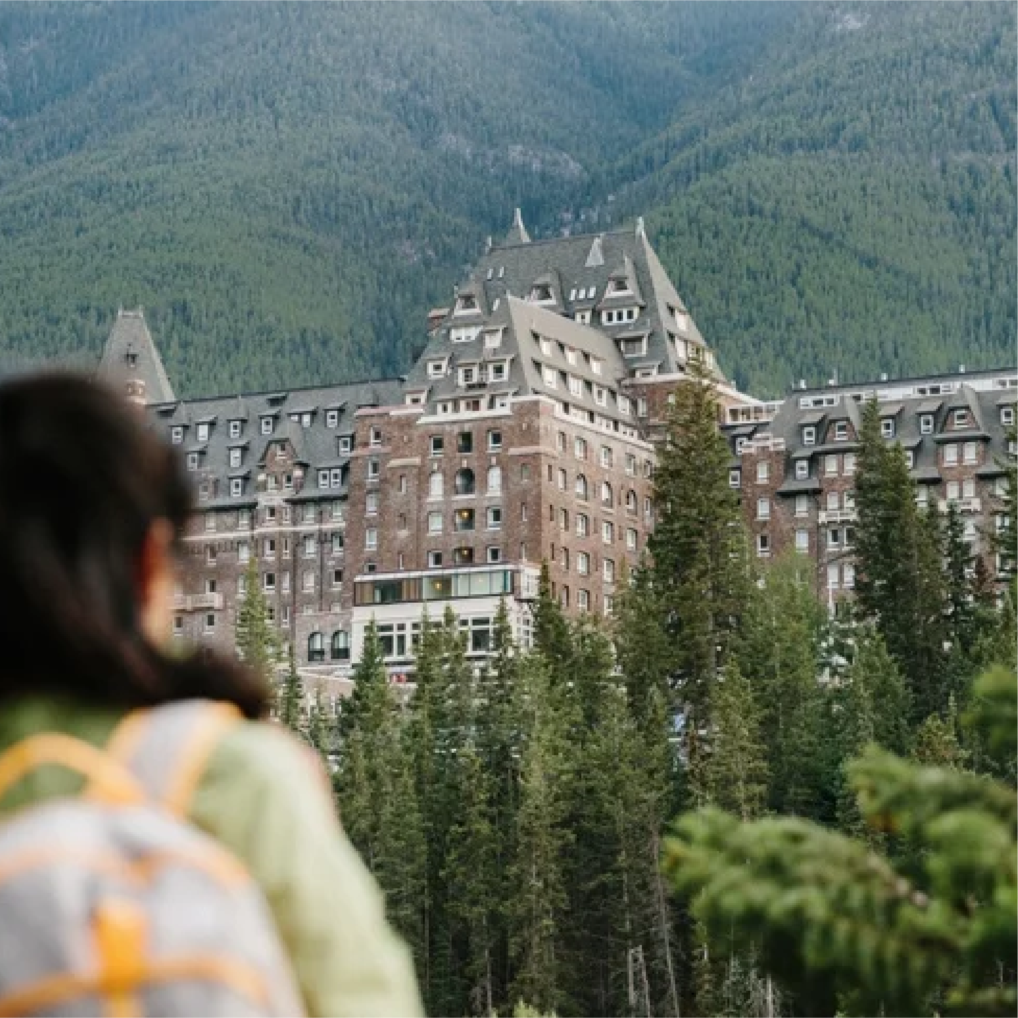 An arial view of Fairmont Banff Springs nestled in nature, surrounded by trees and mountains