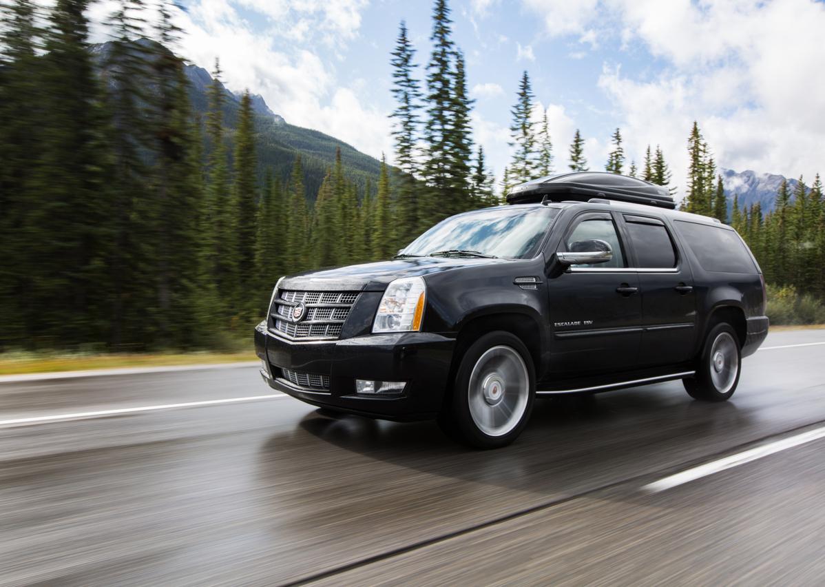 a black SUV driving on a highway with trees and mountains in the background
