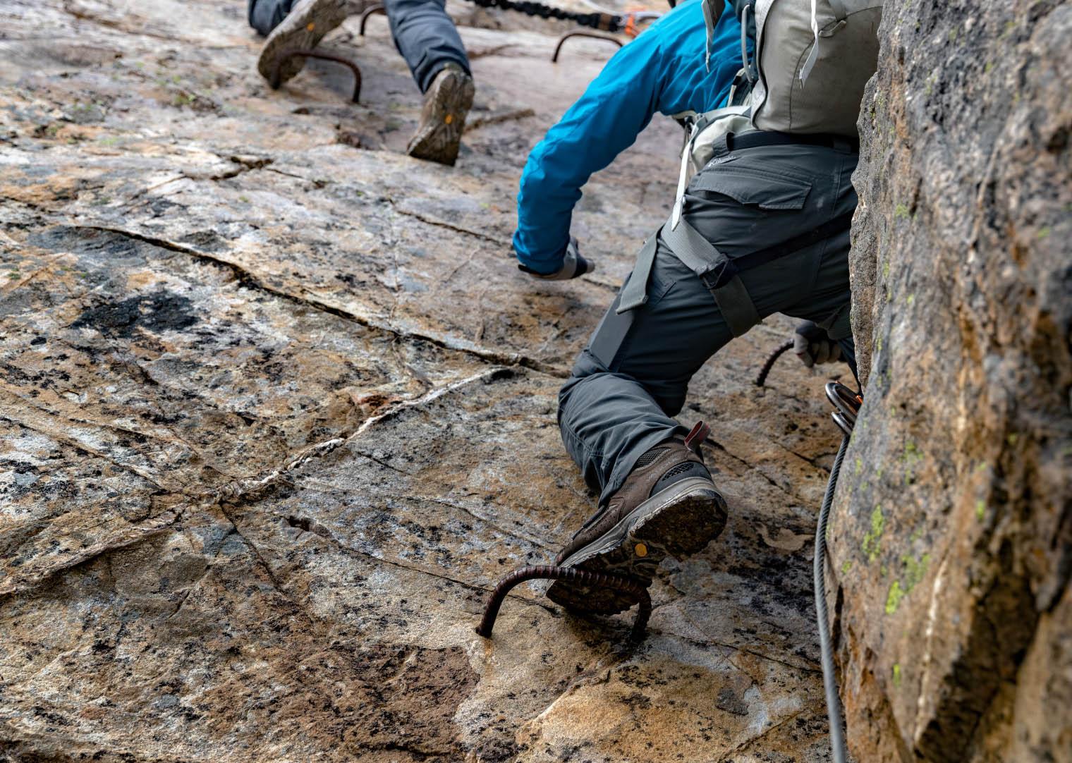 Closeup of boots on via ferrata ladder rungs